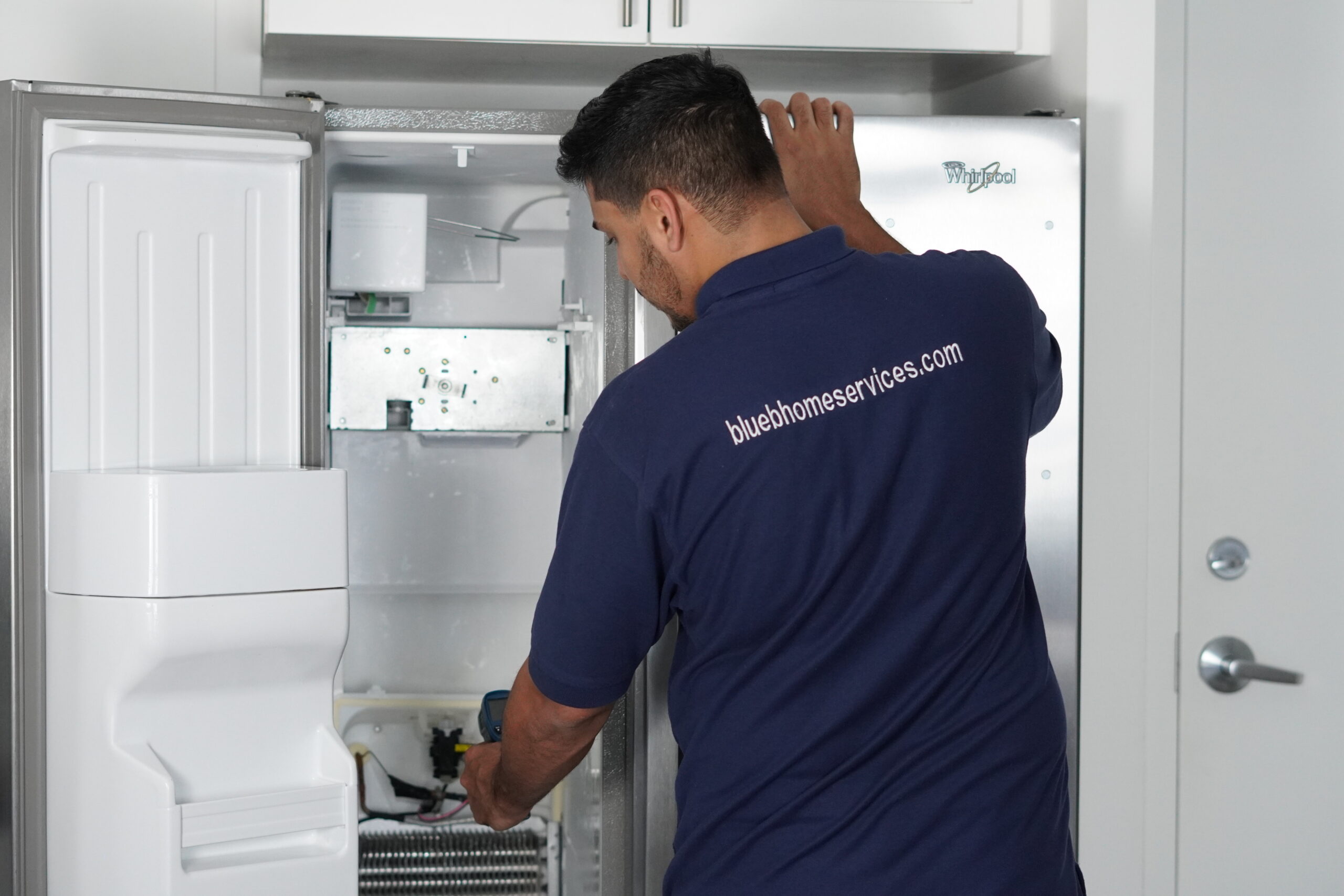 Tech cleaning dusty refrigerator condenser coils in Dania Beach.