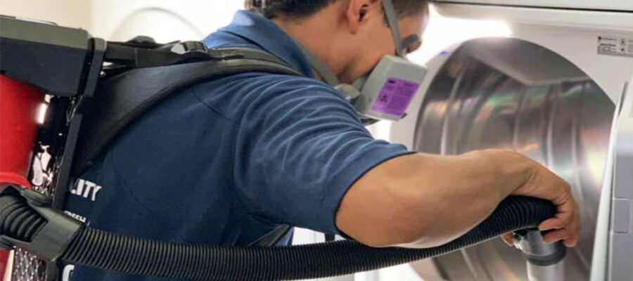 Blue B Home Services technician cleaning a clogged dryer vent in Dania Beach to restore heat.