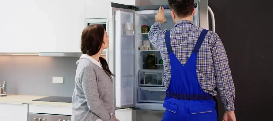 Technician inspecting the ice maker inside a GE refrigerator